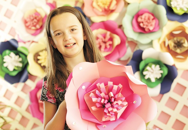 Keira Larson, 9, with paper flowers that she and her family make and sell; proceeds support local animal shelters.