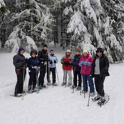 Image: Group of people snowshoeing in a snowy forest.