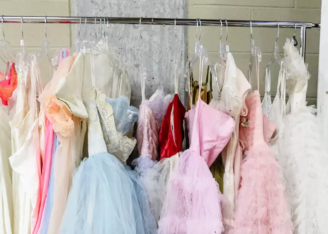 Many vintage pastel-colored dresses hanging on a clothing rack.